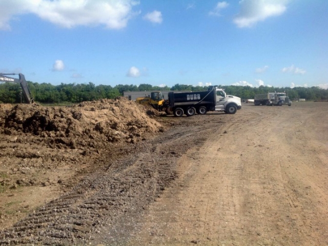 a dump truck lines up next to a pile of dirt