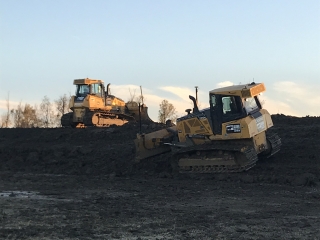 two skidsteers run across a levee