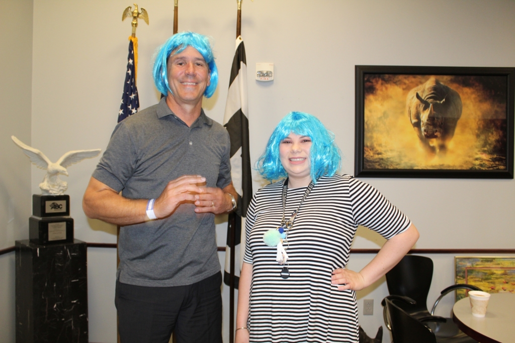 two workers wearing blue wigs pose for the camera