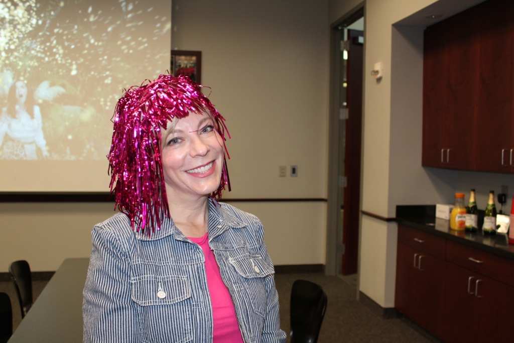 a worker in a pink wig smiles