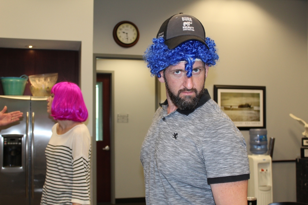 a worker in a blue wig smiles at the camera