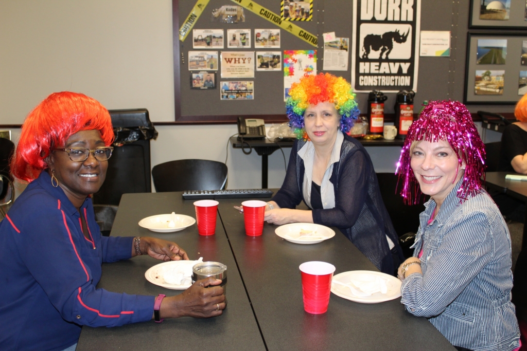 a group of workers in colorful wigs smile at the camera