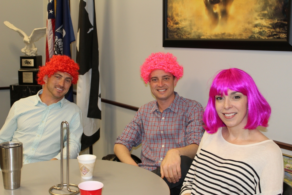 a group of workers in colorful wigs smile at the camera