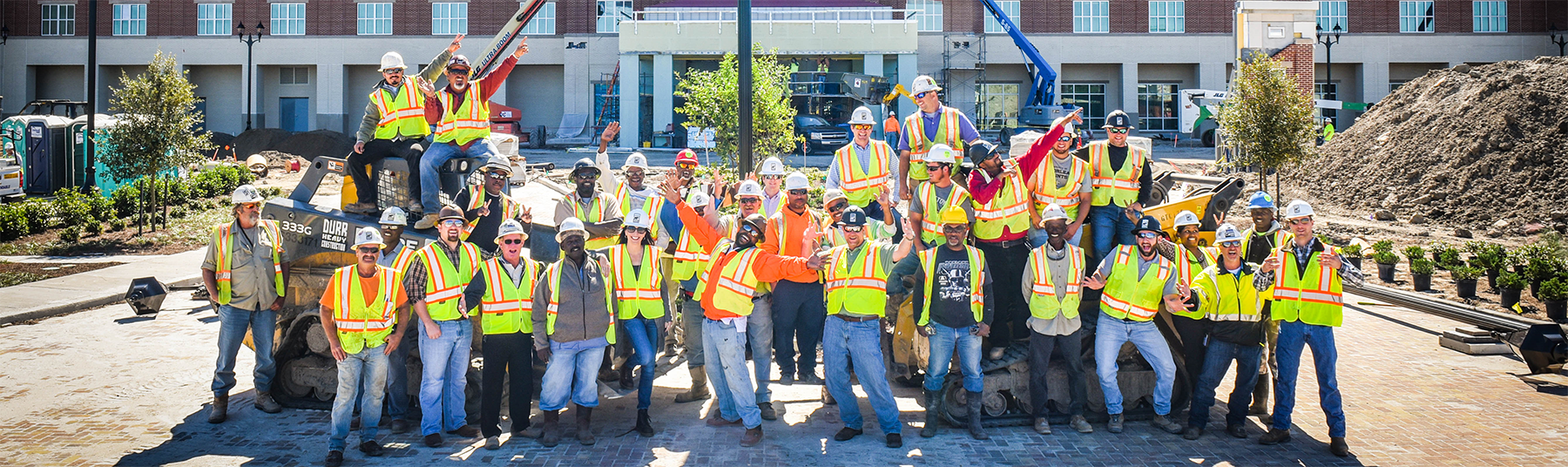 a group shot of Durr employees at a project site with their hands raised in the air for celebration
