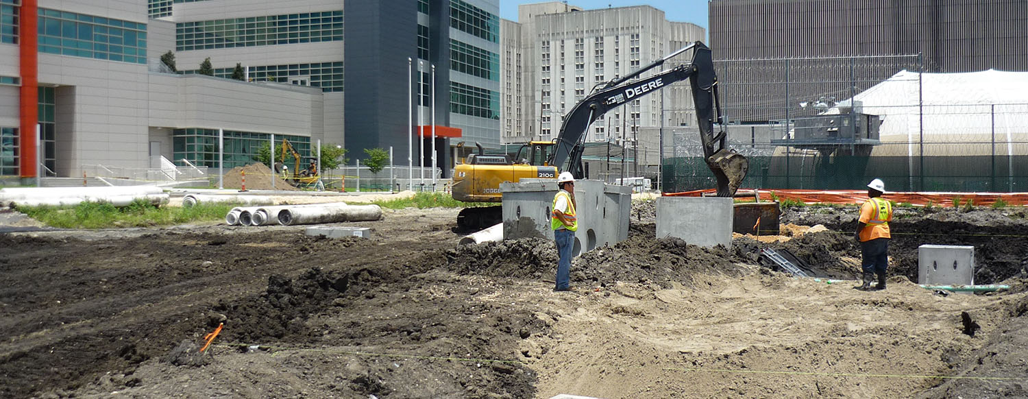 An excavator with two workers standing in front of it